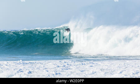 Oceano onda cava grande crash acqua blu con unidentified surfer surf pagaie per la cattura di gonfiarsi incontrano facce nature power. Foto Stock