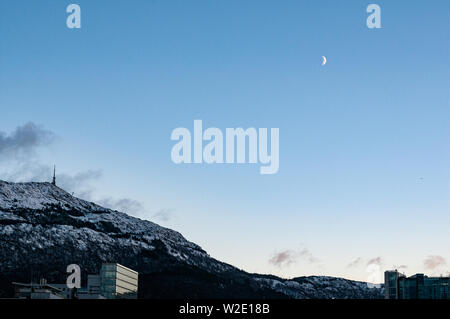 Mount Ulriken nel periodo invernale con una falce di luna. Bergen, Norvegia Foto Stock