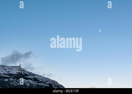 Mount Ulriken nel periodo invernale con una falce di luna. Bergen, Norvegia Foto Stock