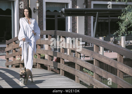 Giovane bella bruna donna passeggiate con il cane sul ponte di legno Foto Stock