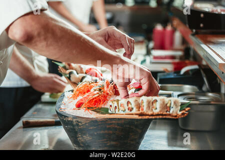 Maschio di cuochi prepara sushi al ristorante cucina Foto Stock