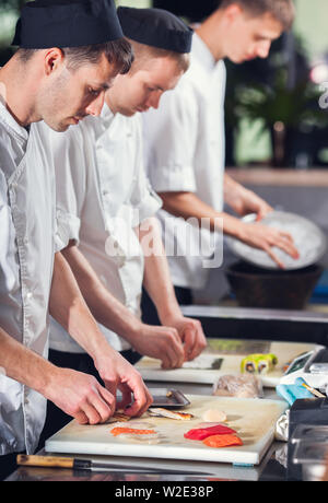 Maschio di cuochi prepara sushi al ristorante cucina Foto Stock