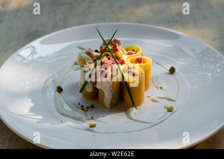 Paccheri fresco italiano la pasta tradizionale con la mortadella Bologna prosciutto cotto, formaggio, crema, i pistacchi,bellissima guarnire la placcatura d'arte chef professionale ammenda Foto Stock