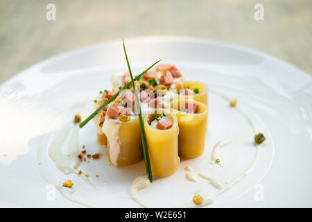 Paccheri fresco italiano la pasta tradizionale con la mortadella Bologna prosciutto cotto, formaggio, crema, i pistacchi,bellissima guarnire la placcatura d'arte chef professionale ammenda Foto Stock