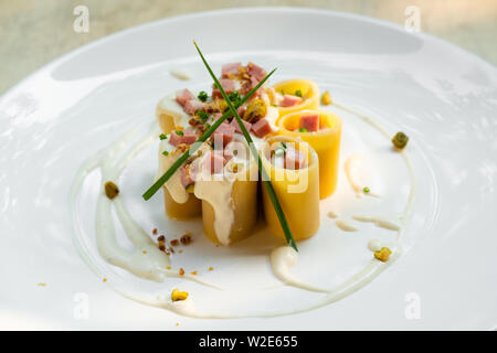 Paccheri fresco italiano la pasta tradizionale con la mortadella Bologna prosciutto cotto, formaggio, crema, i pistacchi,bellissima guarnire la placcatura d'arte chef professionale ammenda Foto Stock