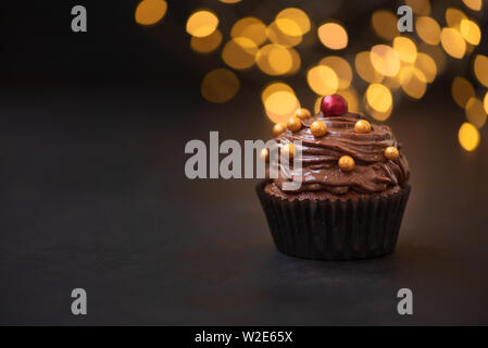 Tortina di cioccolato con golden caramelle sul legno scuro contro lo sfondo sfocato luci. Messa a fuoco selettiva. Alimenti dannosi per la salute. Foto Stock