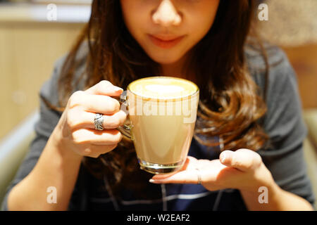 Latte caldo caffè nella ragazza asiatica mano, post e pronto da bere. Foto Stock
