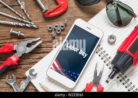 Tabella vista superiore della decorazione il segno di usa la giornata del lavoro il concetto di sfondo. Lay piatto mock up Smart Phone con la Giornata del Lavoro USA Holiday ed essenziali di const Foto Stock