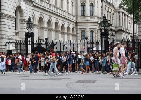 London, Regno Unito - Luglio 2019: un folto gruppo di bambini della scuola di raccolte al di fuori del cancello di sicurezza per 10 Downing Street, casa del Primo Ministro britannico. Foto Stock