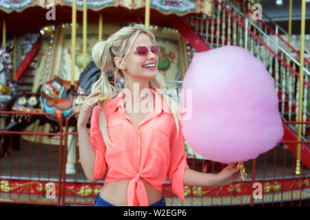 Giovane donna bionda azienda rosa confetto e ridere. Foto Stock