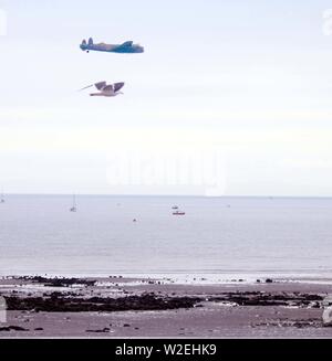 L'Avro Lancaster del Battle of Britain Memorial Flight (BBMF) racing un gabbiano locali al di sopra del mare nella baia di Swansea durante il Galles Air Show, Luglio Foto Stock