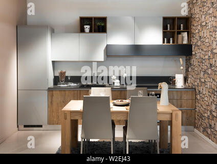 Compact moderna cucina o angolo cottura con costruito in armadi e apparecchi piano aperto per un piccolo design contemporaneo chunky tavolo e sedie Foto Stock