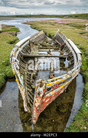 Un vecchio rotto naufragio di una barca da pesca di sinistra sul marsh ingresso al mare. Questa è stata scattata nella contea di Mayo in Irlanda. Foto Stock