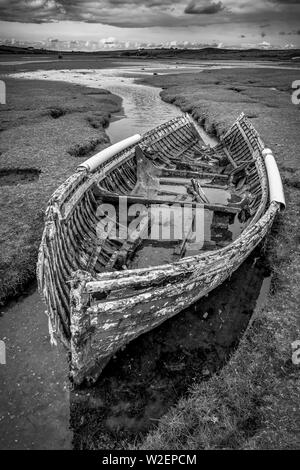 Un vecchio rotto naufragio di una barca da pesca di sinistra sul marsh ingresso al mare. Questa è stata scattata nella contea di Mayo in Irlanda. Foto Stock