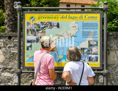 LENNO, LAGO DI COMO, Italia - Giugno 2019: le persone che ricercano una mappa della Greenway del lago di Como a Lenno sul Lago di Como. La Greenway è un itinerario a piedi Foto Stock