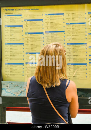 VARENNA, LAGO DI COMO, Italia - Giugno 2019: Persona che controlla il calendario di traghetto al porto di Varenna sul lago di Como, Italia. Foto Stock