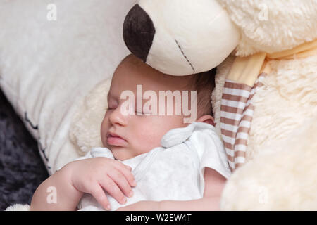 Tranquillo sonno neonato con il gigante fluffy Teddy bear Foto Stock