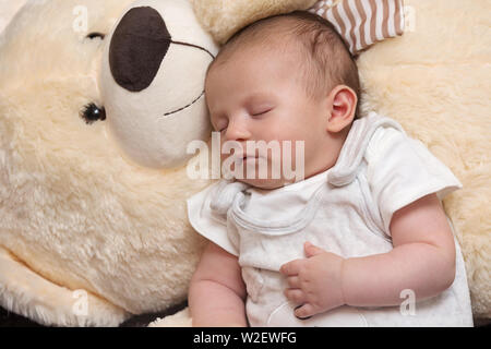 Tranquillo sonno neonato con il gigante fluffy Teddy bear Foto Stock