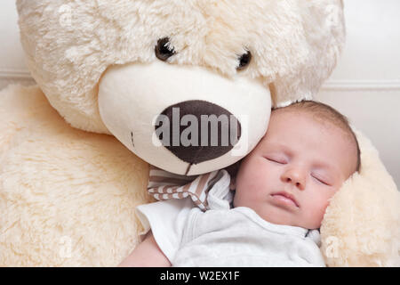 Tranquillo sonno neonato con il gigante fluffy Teddy bear Foto Stock