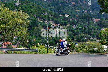 Turista giovane su un ciclomotore,attesa al traffico stradale luce,sulla strada giù da Paleokastritsa monastero,Theotokos Monastero, Corfù, Grecia Foto Stock