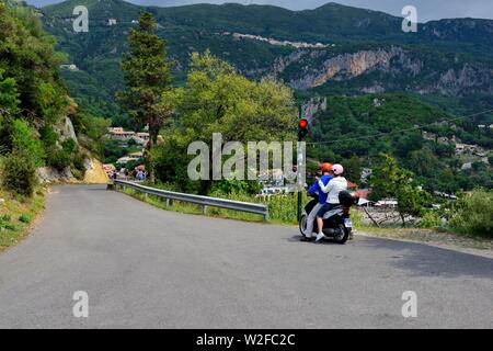 Turista giovane su un ciclomotore,attesa al traffico stradale luce,sulla strada giù da Paleokastritsa monastero,Theotokos Monastero, Corfù, Grecia Foto Stock