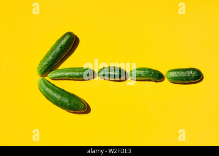 Dimensioni diverse forme cetrioli pattern su uno sfondo giallo formano un simbolo a forma di freccia. La strada per il successo, vittoria, conseguimento degli obiettivi, risultato Foto Stock