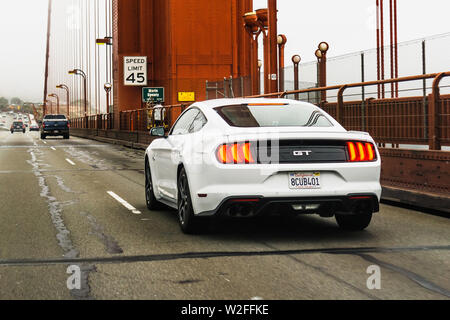 Luglio 4, 2019 San Francisco / CA / STATI UNITI D'AMERICA - Bianco Ford Mustang GT che viaggiano sul Golden Gate Bridge; vista posteriore Foto Stock