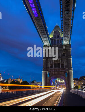 Sentieri di luce dal traffico che passa al di sopra della mitica il Tower Bridge di Londra. Il Gherkin grattacielo e la Torre di Londra può essere visto in lontananza. Foto Stock