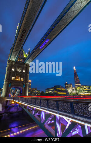 London, Regno Unito - 24 Giugno 2019: sentieri di luce da una barca passando sotto il Ponte della Torre e sentieri di luce dal traffico passando sopra il ponte. Il Foto Stock