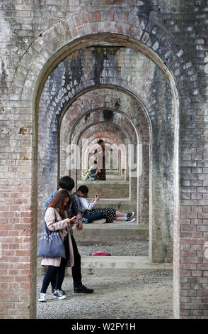 Giapponese coppie youg rilassante sotto Suirokaku mattone acquedotto, tempio di Nanzenji, Kyoto, Giappone Foto Stock