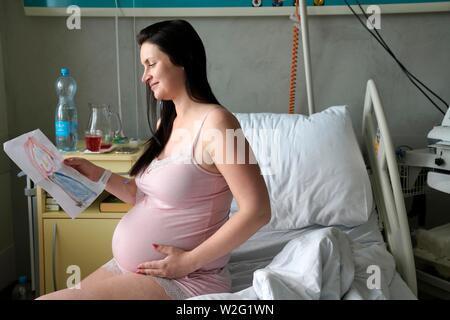 Donna incinta seduta su sickbed nella stanza di ospedale con immagine di bambino, ad alto rischio di gravidanza, Karlovy Vary, Repubblica Ceca Foto Stock