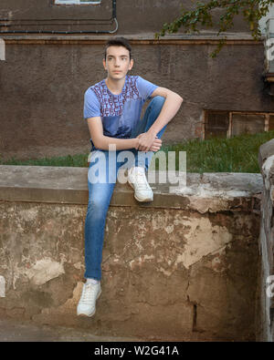 Ragazzo adolescente seduto sulla strada Foto Stock