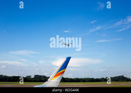 Un piccolo aereo atterra appena al di là di wingtip di un sistema Allegiant Airbus A320 aereo jet a Orlando Sanford International Airport in Sanford, Florida, Stati Uniti d'America. Foto Stock