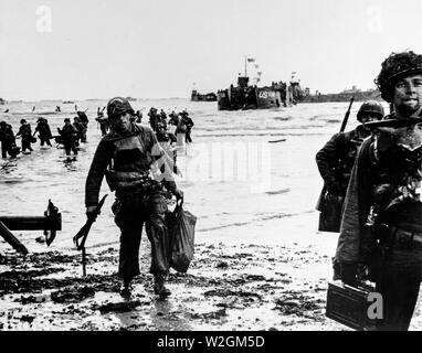 [Didascalia originale] Invasione ... Che trasportano attrezzatura completa, American assalto delle truppe si muovono su di una testa di ponte sulla costa settentrionale della Francia . Landing Craft, in background, marmellate del porto. Giugno 6, 1944. La spiaggia di Omaha. Foto Stock