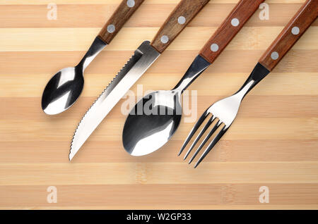 Set di posate su un tavolo di legno. Coltello, forchetta, cucchiaio. Foto Stock