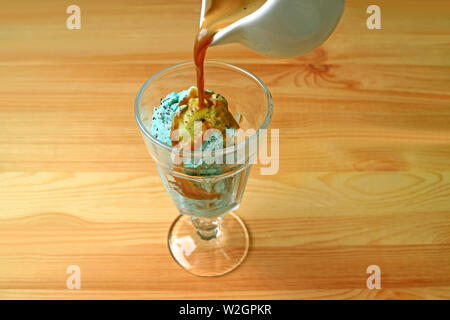 Caffè espresso di essere versata su mint chocolate chip ice cream per un Affogato Foto Stock