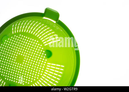 Close-up di un verde scolapasta plastica, un arnese da cucina a scolare la pasta su uno sfondo bianco. Foto con copia spazio. Foto Stock