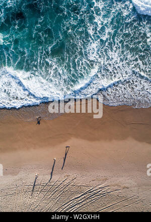 Antenna della gente che cammina su una spiaggia al tramonto con la bella spiaggia di sabbia e Gentle Waves Foto Stock