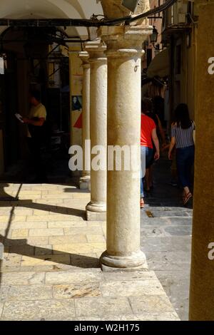 La città di Corfù street con pilastri di pietra nel centro della città. un sacco di sole e ombra nella scena molto poche persone Foto Stock