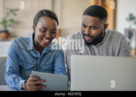 Sorridente giovane africano coppia americana lavora online insieme a casa Foto Stock