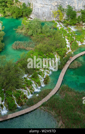 Gli escursionisti passando le cascate di acqua correre verso il basso nel colore turchese Lago Kaluđerovac presso il Parco Nazionale dei Laghi di Plitvice in Croazia Foto Stock