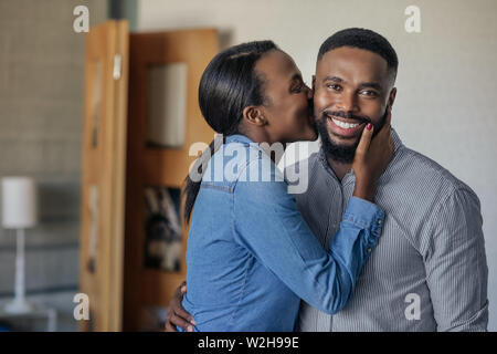 Affettuosa African American moglie baciare il marito sulla guancia Foto Stock