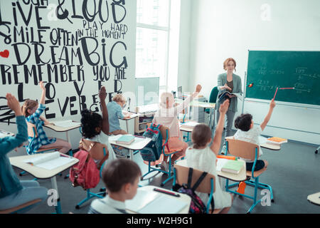 Quasi tutti i bambini in classe ad alzare la mano. Foto Stock