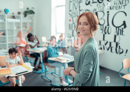 Bella insegnante in piedi nella parte anteriore della sua classe. Foto Stock