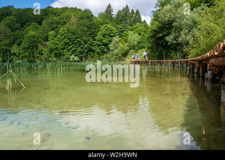 Gli escursionisti passando un bellissimo paesaggio con turchesi laghi nascosti nella natura selvaggia del Parco Nazionale dei Laghi di Plitvice in Croazia Foto Stock