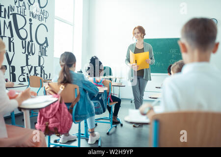 Insegnante in piedi di fronte a lei gli alunni della classe. Foto Stock
