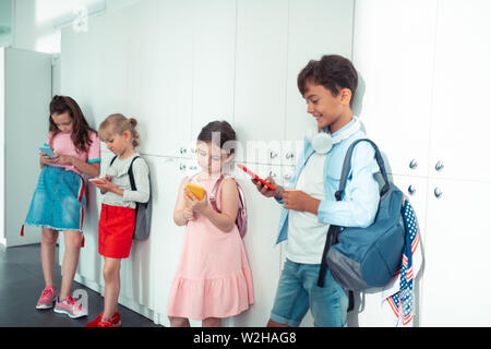 I bambini in piedi vicino gli armadietti e la riproduzione di video giochi Foto Stock