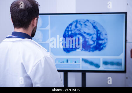 Maschio di medico in ospedale esplora il cervello di tomografia sul monitor. Controllo medico il paziente braind dopo una scansione TC. Foto Stock