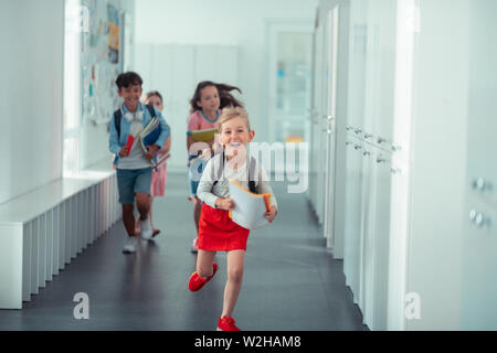 Felice ragazza indossare gonna rosso acceso a casa da scuola Foto Stock