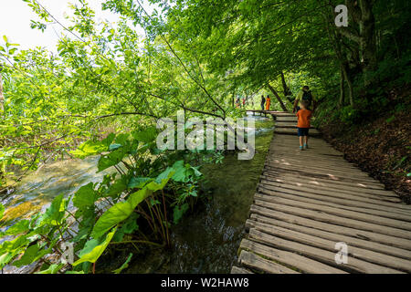 Gli escursionisti passando un bel paesaggio di laghi e stagni e fiumi a cascata nascosto nel deserto del Parco Nazionale dei Laghi di Plitvice in Croazia Foto Stock